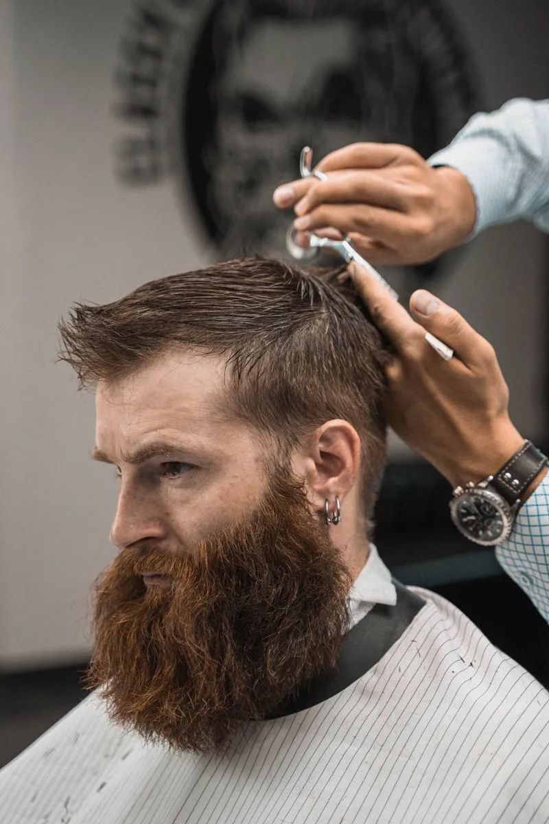 Barbero realizando un corte profesional a un cliente en una barbería moderna.