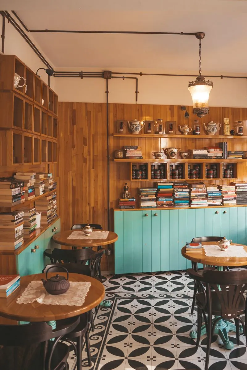 Interior cálido de una cafetería de especialidad con mesas, libros y buena ambientación.